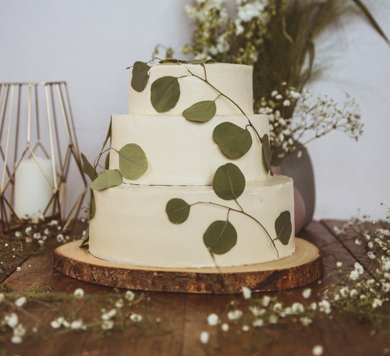 White Buttercream Cake on Tree Slice Cake Stand with Foliage Decor