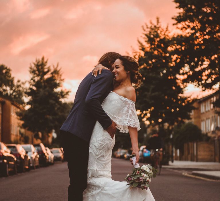 Pink Sunset Portrait with Bride in Off The Shoulder Grace Loves Lace Dress and Groom in Blue Blazer