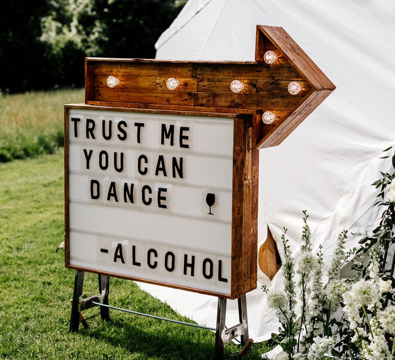 Wooden Wedding Sign // Bride In Floral Dress By Stephanie Allin Festival Wedding With Food Trucks &amp; Outdoor Ceremony With Geo Dome Tent Baya Hire Epic Love Story Photography