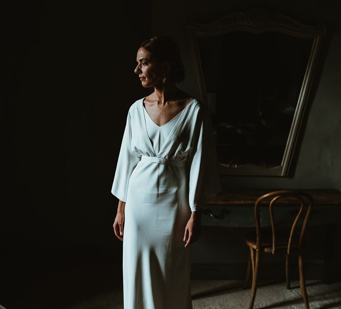 Bride wearing elegant Charlie Brear dress with long sleeve bridal top and belt