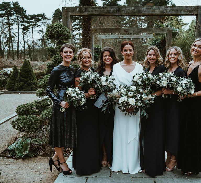 Bride and her bridesmaids wearing black dresses and white floral bouquets