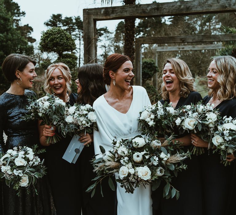 Bride and her bridesmaids wearing black dresses and white floral bouquets