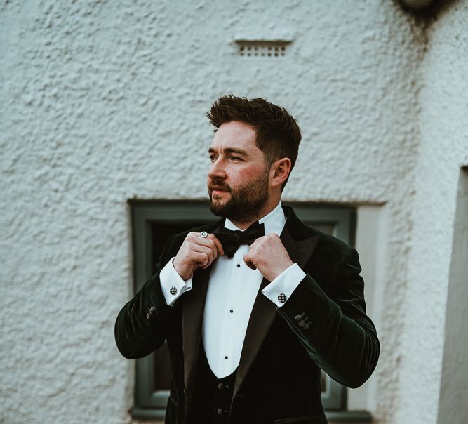 Groom wearing custom made velour three piece suit and bow tie at winter wedding