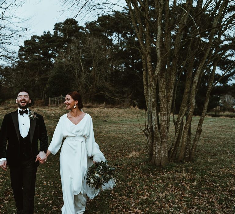 Bride wearing elegant dress and white floral bouquet with her groom wearing three piece suit and bow tie