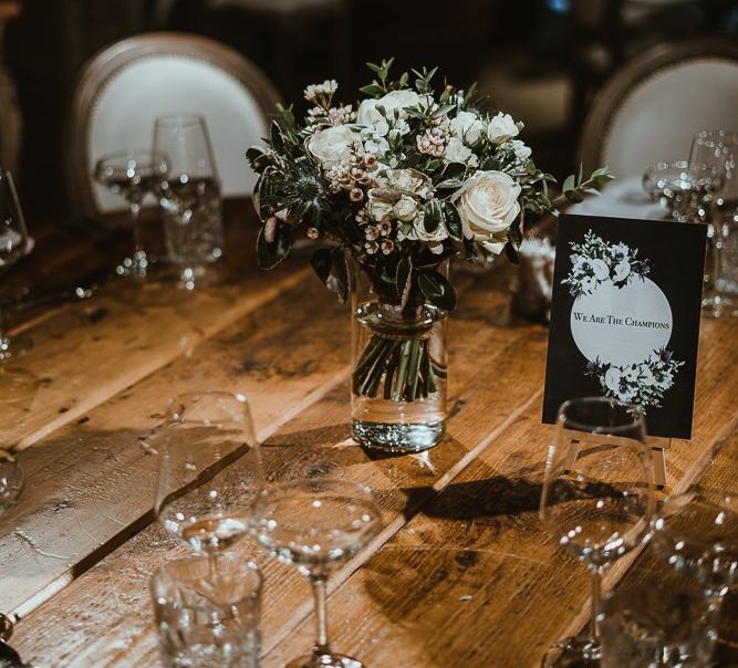 Table settings at winter wedding with white floral arrangements and black &amp; white stationery