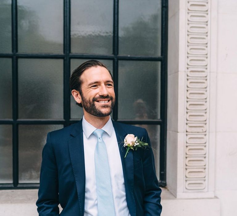 Groom in navy blue suit and baby blue tie for intimate wedding