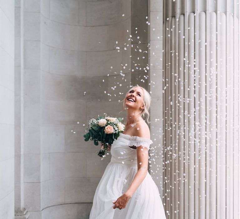 Confetti moment with pregnant bride in maternity wedding dress