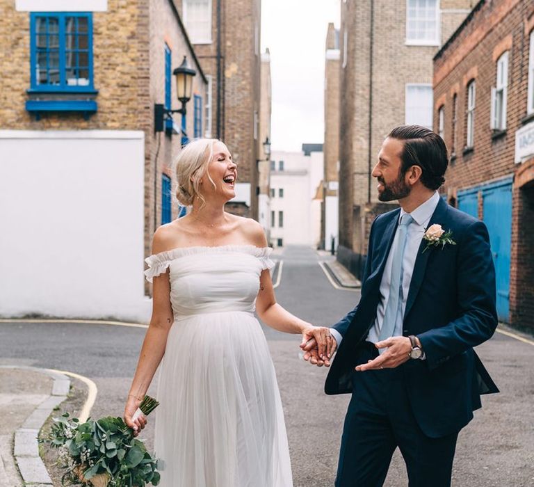 Pregnant bride in maternity wedding dress and groom in navy suit in London streets