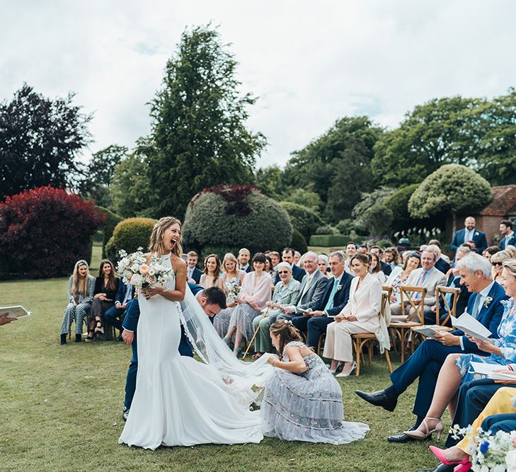 Bridesmaid in Needle and Thread Dress Adjusting the Brides Train at the Outdoor Wedding Ceremony Altar