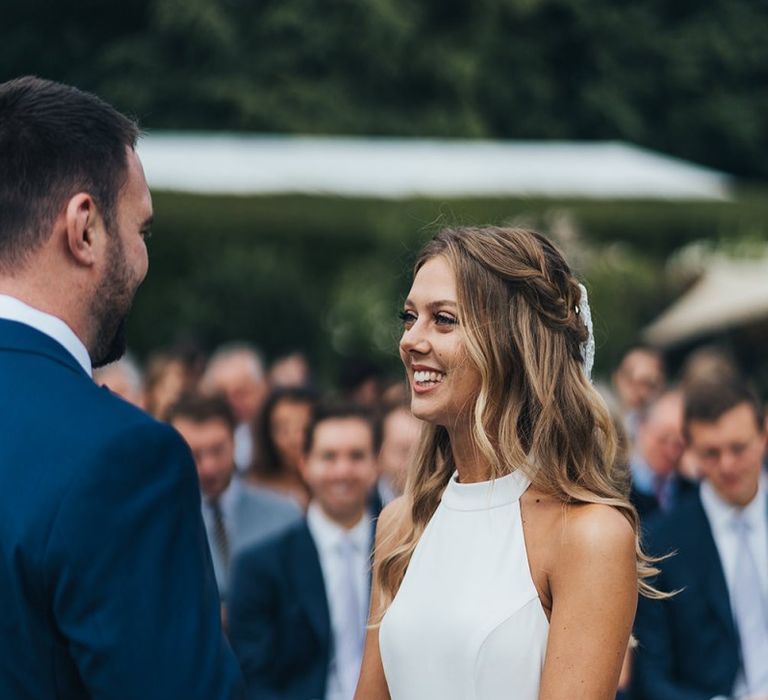 Bride in Halterneck Wedding Dress Smiling at Her Groom During The Outdoor Wedding Ceremony