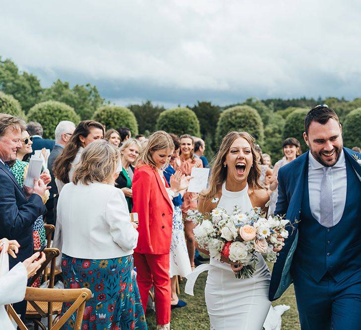 Bride in Halterneck Wedding Dress and Groom in Navy Suit Walking Up the Aisle as Husband and Wife