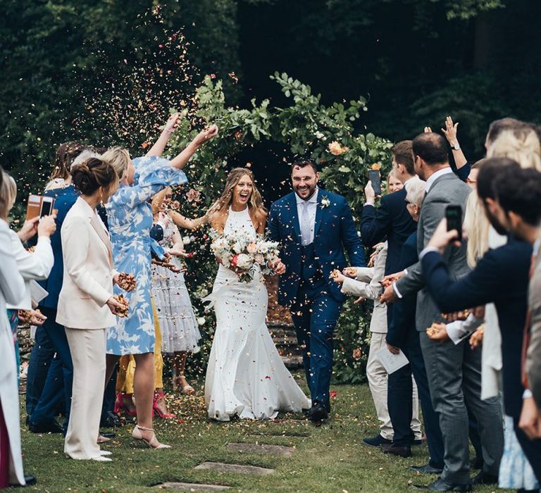 Confetti Moment with Bride in Halterneck Wedding Dress and Groom in Navy Suit with Horseshoe Waistcoat