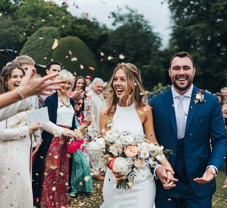 Confetti Moment with Bride in Made With Love Wedding Dress Holding a Spring Bouquet and Groom in Three-Piece Navy Suit