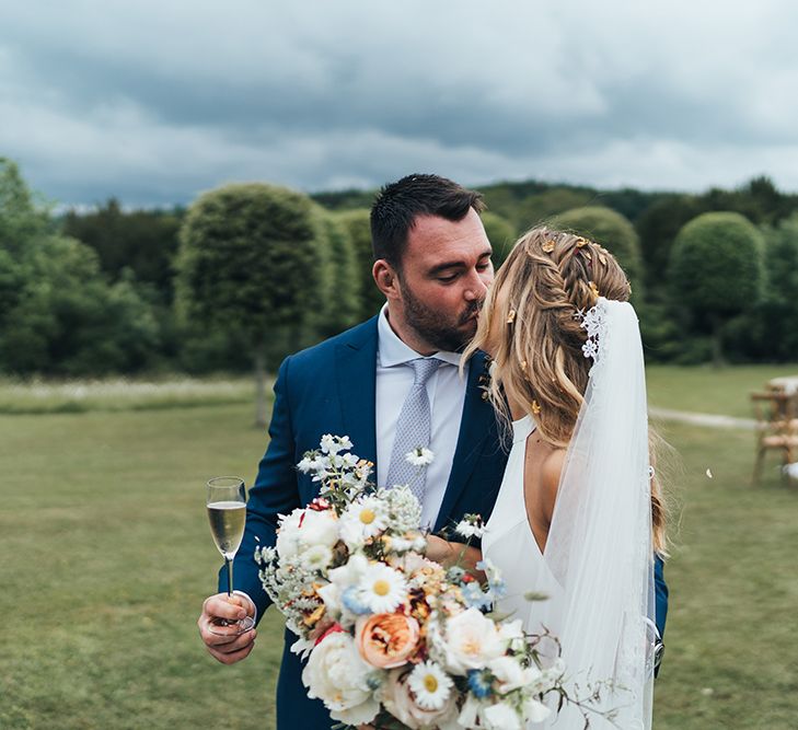 Groom Kissing His Bride with Braided Half Up Half Down Hair and Cathedral Length Veil