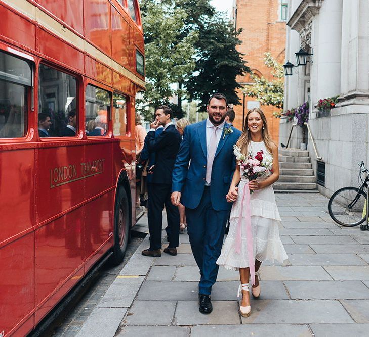 Happy Couple Walk Next To Bus Wedding Transport