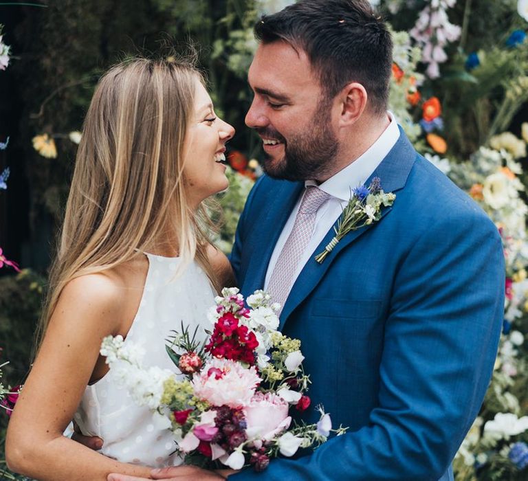 Bride and Groom In Navy Suit With Pink Flowers