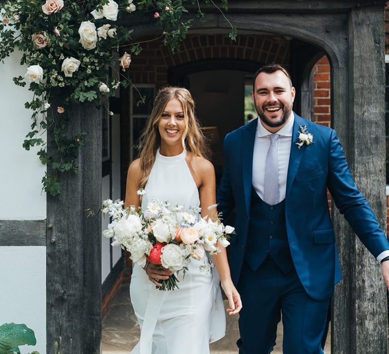 Bride in Halterneck Made With Love Wedding Dress and Groom in Navy suit with Horseshoe Waistcoat