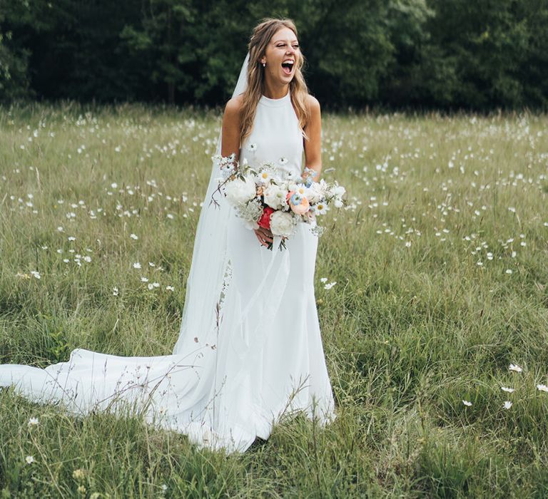 Bride in Halterneck Made With Love Wedding Dress Holding a Romantic Wedding Bouquet in a Field