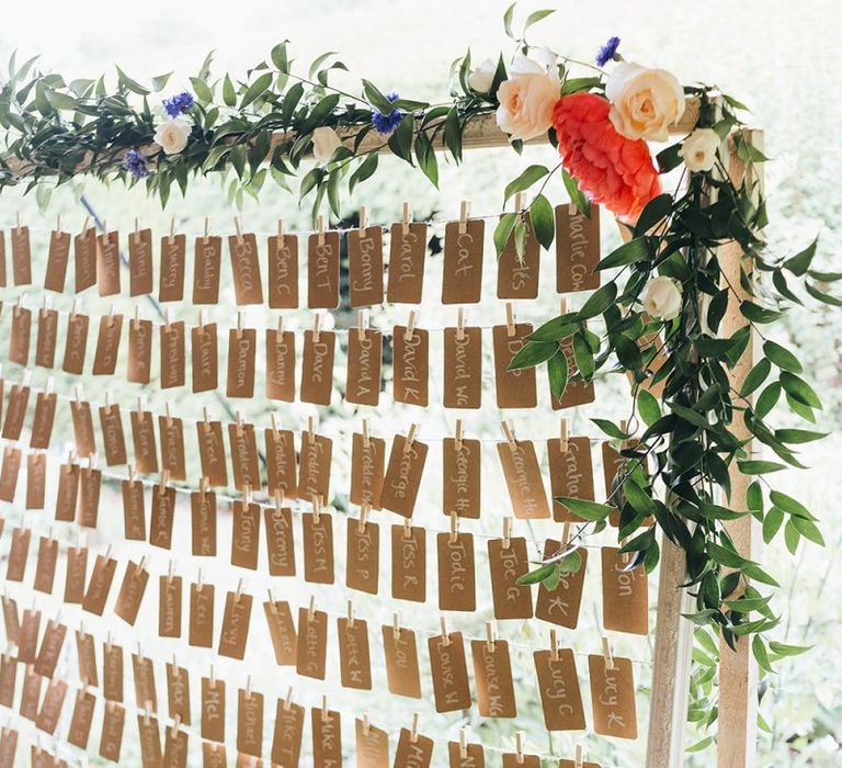 Craft Paper Escort Cards Pegged on a Giant Wooden Frame Decorated with Vine and Flowers