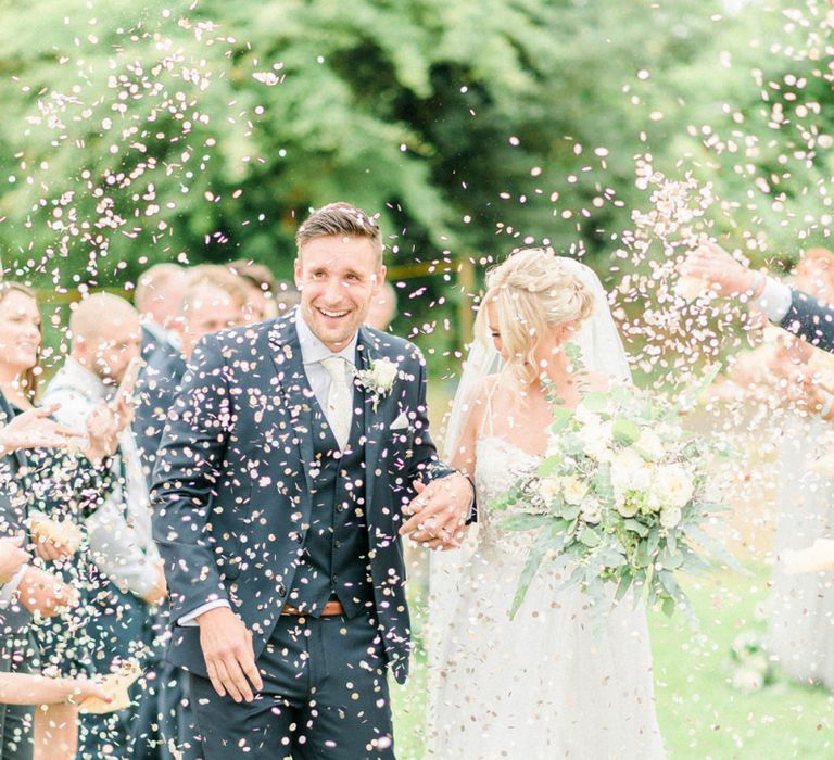 Confetti Moment with Bride in Romantic Wedding Dress and Groom in Navy Moss Bros. Suit