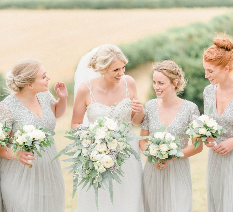 Bride in Lace Bodice Wedding Dress with Floaty Skirt and Straps Laughing with Bridesmaid in Lace &amp; Sequin MAYA Dresses