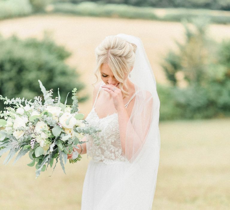 Bride in Embellished Bodice Wedding Dress and Cathedral Veil Holding a White and Green Wedding Bouquet