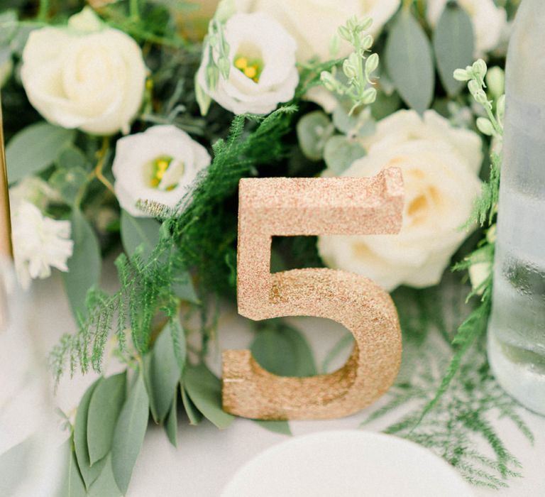 Table Centrepiece with White and Green Flowers, Church Candle and Gold Glitter Table Number for Wedding