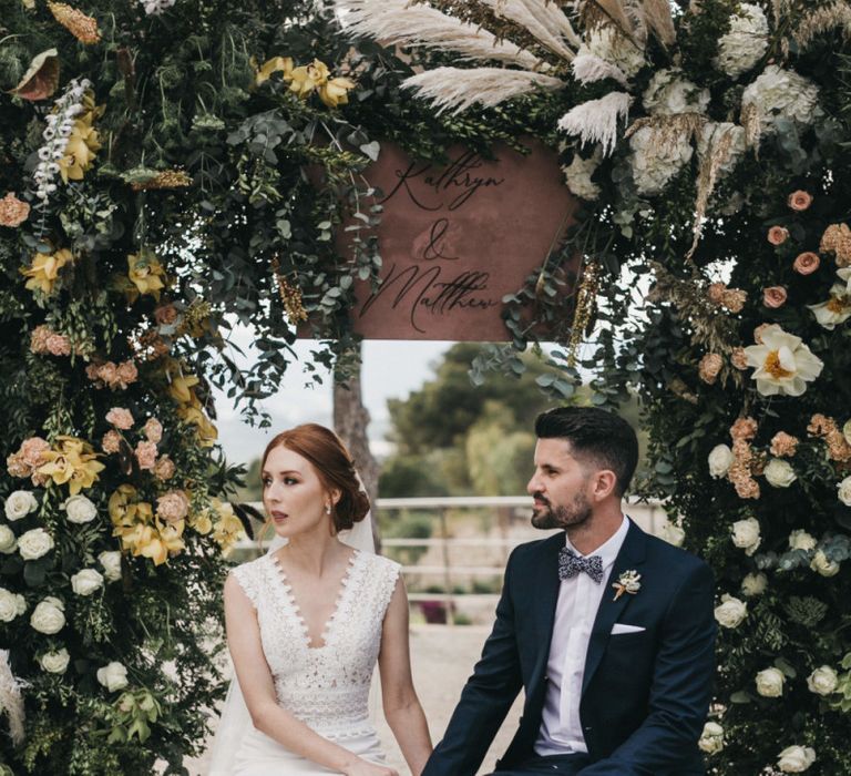 Bride in Pronovias Wedding Dress and Groom in Navy Suit Holding Hands During the Wedding Ceremony