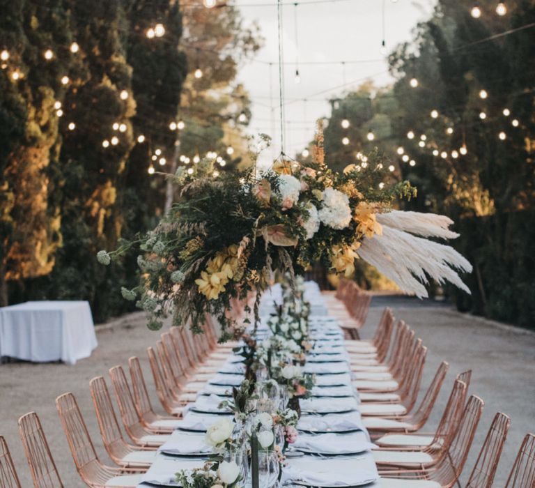 Long Wedding Reception Table with Peach Flowers, Pampas Grass Installation and Festoon Lights