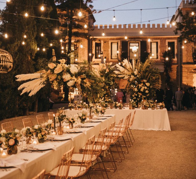 Outdoor Spanish Wedding Reception with Festoon Lights and Flower Installation