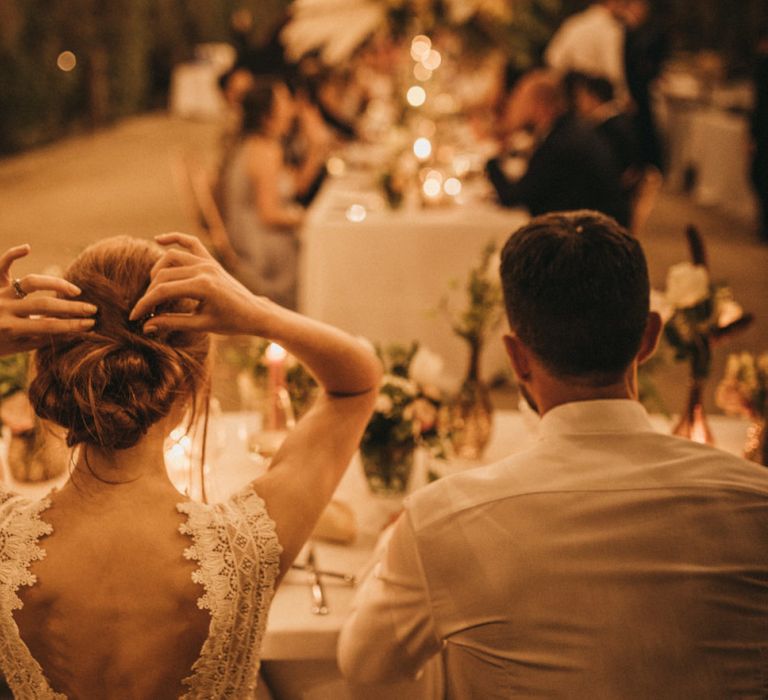 Bride in Lace Low Back Wedding Dress Sitting at the Top Table