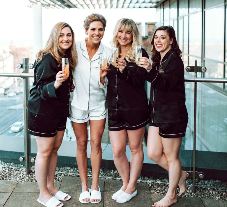 Bridal party in black and white getting ready robes drinking mimosas