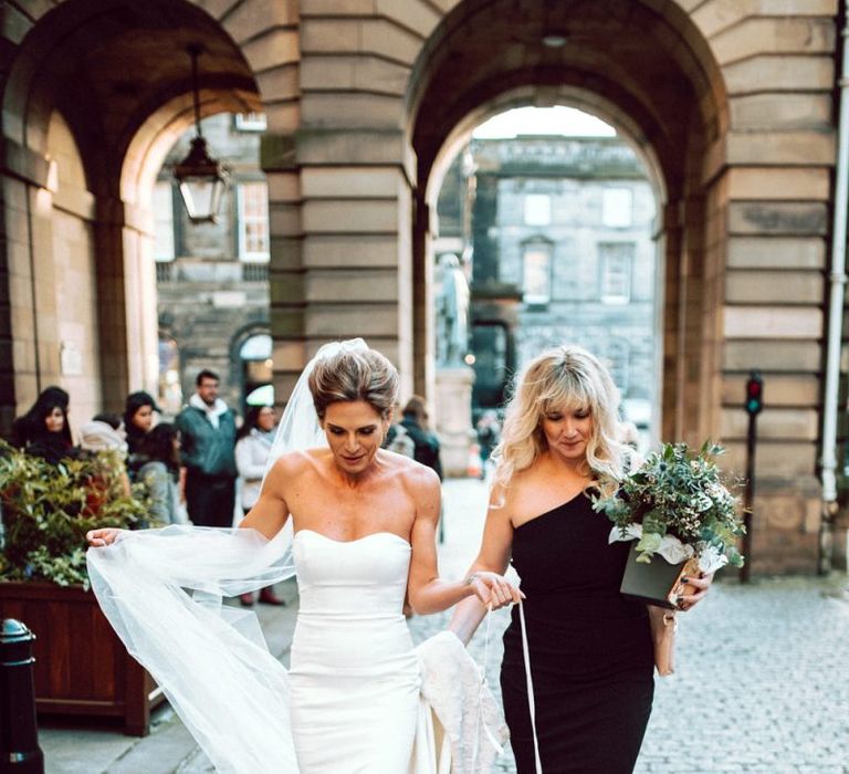 Bride and bridesmaid in black dress entering the Edinburgh City Chambers wedding ceremony