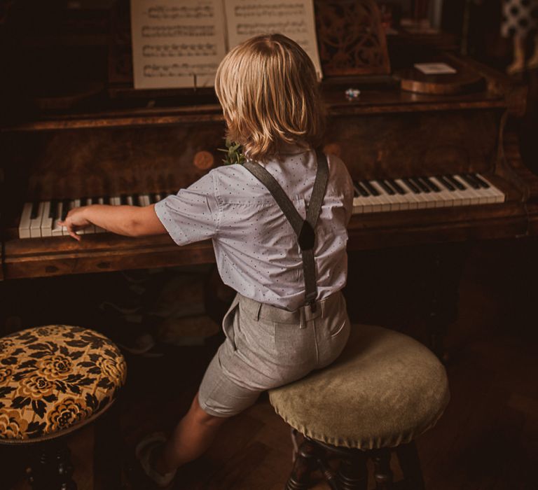 Young Boy in Shorts and Blazer Sitting at a Piano