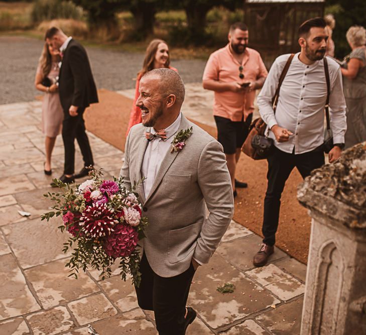 Groom in Grey Blazer and Bow Tie Holding a Pink Wedding Bouquet featured on escape to the chateau