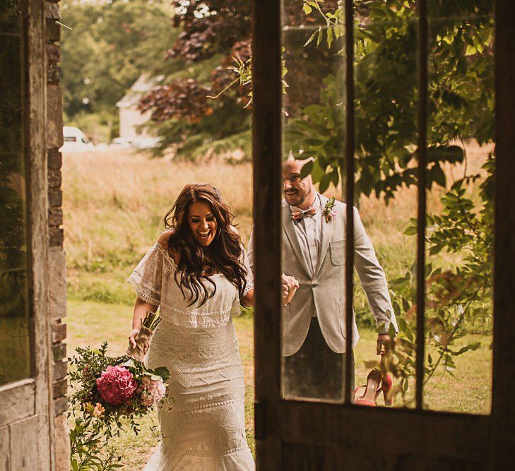 Bride in Emanuela Grace Loves Lace Wedding Dress and Groom in Grey Blazer Walking into the French Chateau Wedding Reception