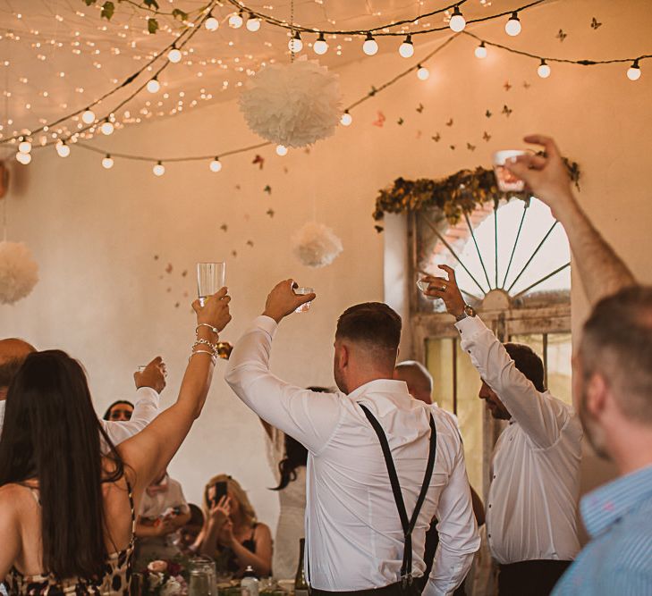 Wedding Guests Raising a Glass in the Festoon Lit Wedding Reception