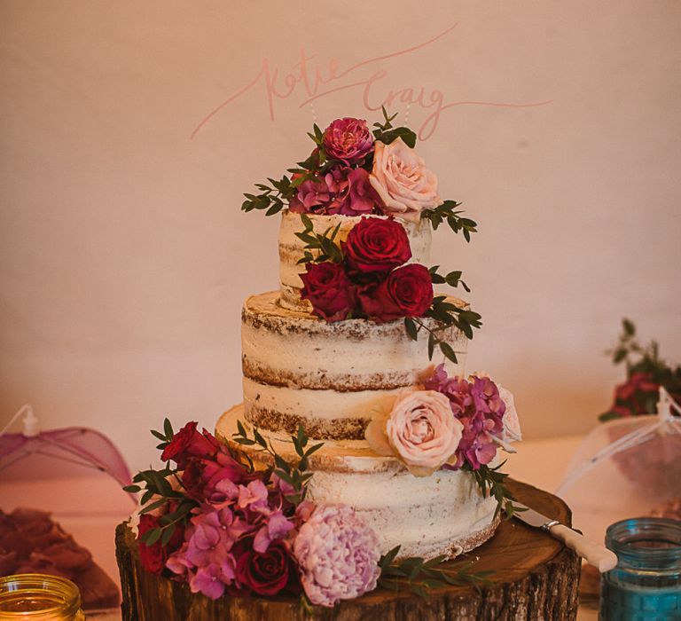 Semi Naked Wedding Cake Decorated with Pink Flowers on a Rustic Tree Slice Cake Stand escape to the chateau