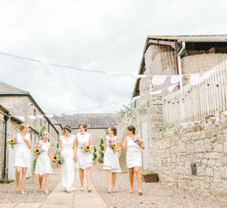 Bride in Chiffon Polka Dot Dress by Kate Halfpenny | Bridal Flower Crown | Bridesmaids in Mismatched Knee-Length White Dresses | Bright Bouquets with Sunflowers | Bridal Plaited Up Do | White Bunting | Colourful Paper Cranes &amp; Sunflower Wedding Décor in Rustic Barn | Sarah-Jane Ethan Photography