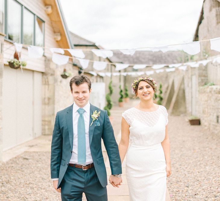 Bride in Chiffon Polka Dot Dress by Kate Halfpenny | Bridal Flower Crown | Groom in Blue Hugo Boss Suit with Dusty Blue Tie | Bright Bouquet with Sunflowers | Bridal Plaited Up Do | White Bunting | Colourful Paper Cranes &amp; Sunflower Wedding Décor in Rustic Barn | Sarah-Jane Ethan Photography