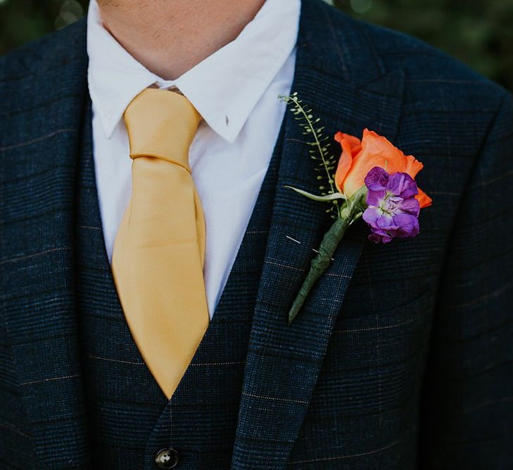 Groom wears yellow tie to match the canary yellow bridesmaid dresses with bright floral buttonhole