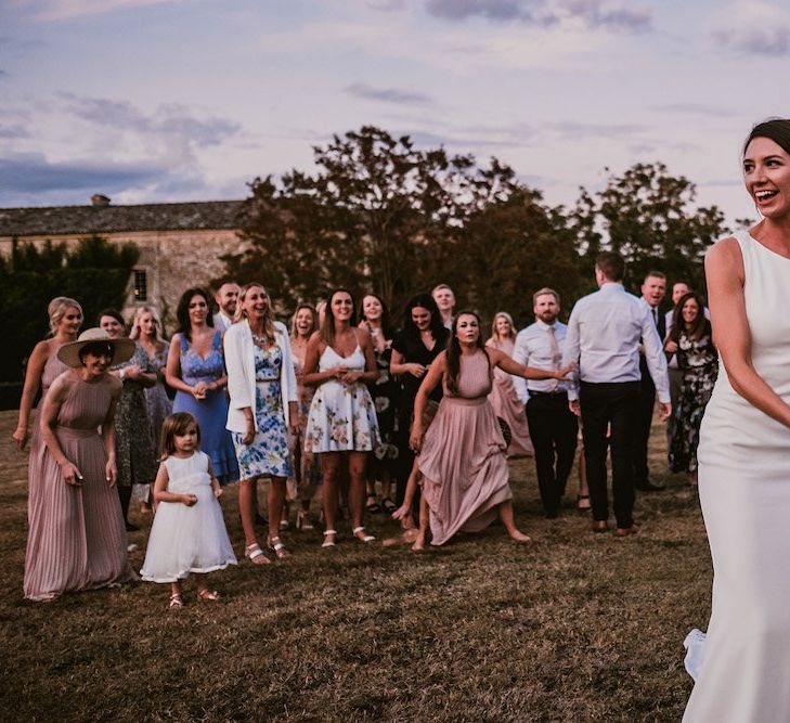 Bride in Pronovias dress throws bouquet to guests