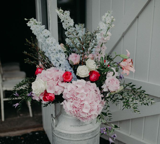 Milk churn filled with pastel pink and blue wedding flowers