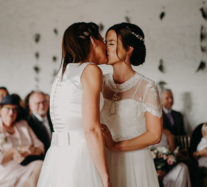 Same sex wedding with two brides kissing at the altar