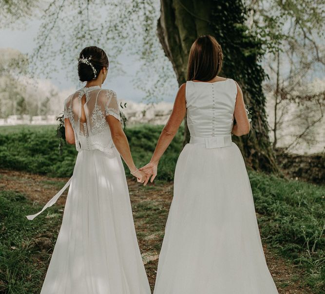 Same sex wedding with two brides in Satin and tulle dress and Lace and chiffon wedding dress holding hands