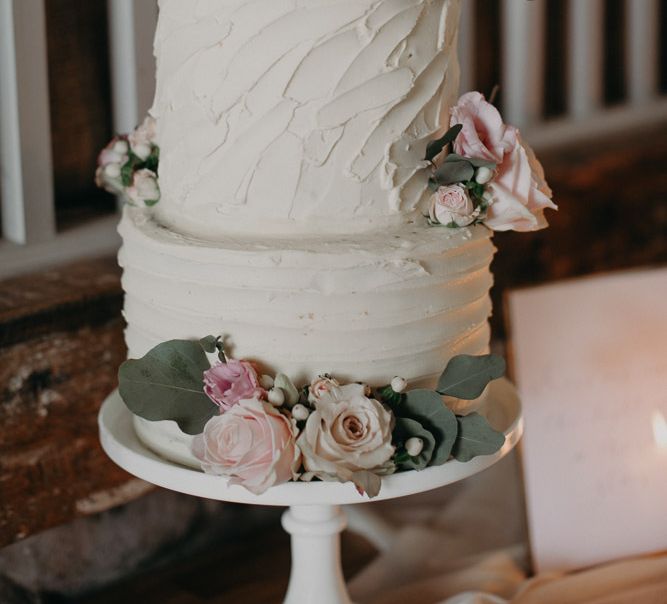 Three tier buttercream cake with roses and eucalyptus decor