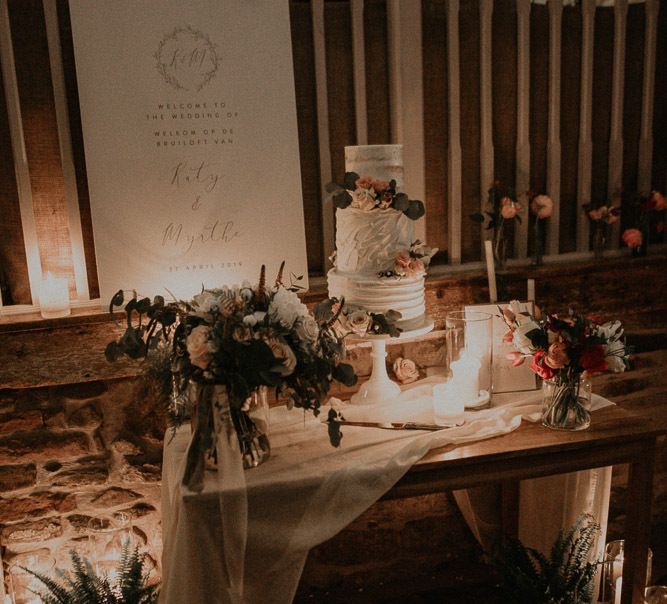 Wedding cake table with romantic candlelight, drapes and flowers decor