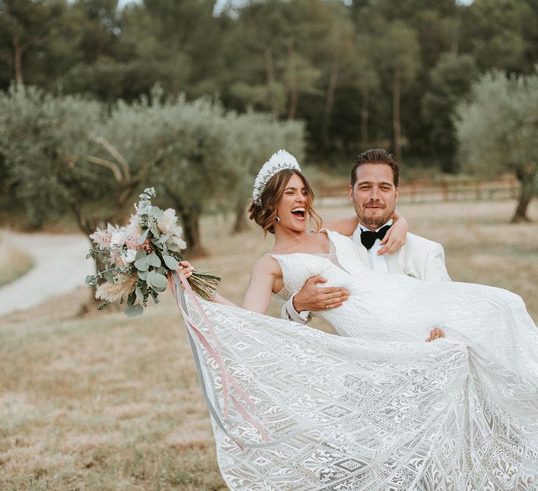 Groom Lifts Bride In Lace Dress With Feather Headdress