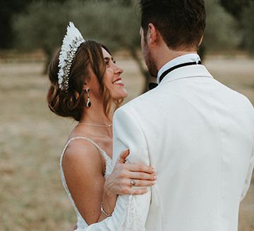 Bride Wears Feather Headdress And Gazes At Husband In White Dinner Jacket