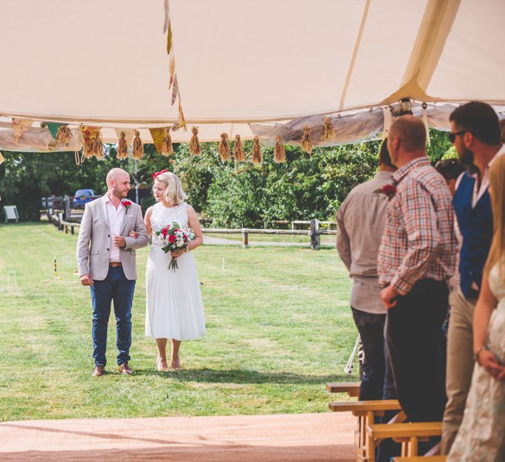 Marquee wedding with bright bunting decoration and bride wearing midi pleated wedding skirt